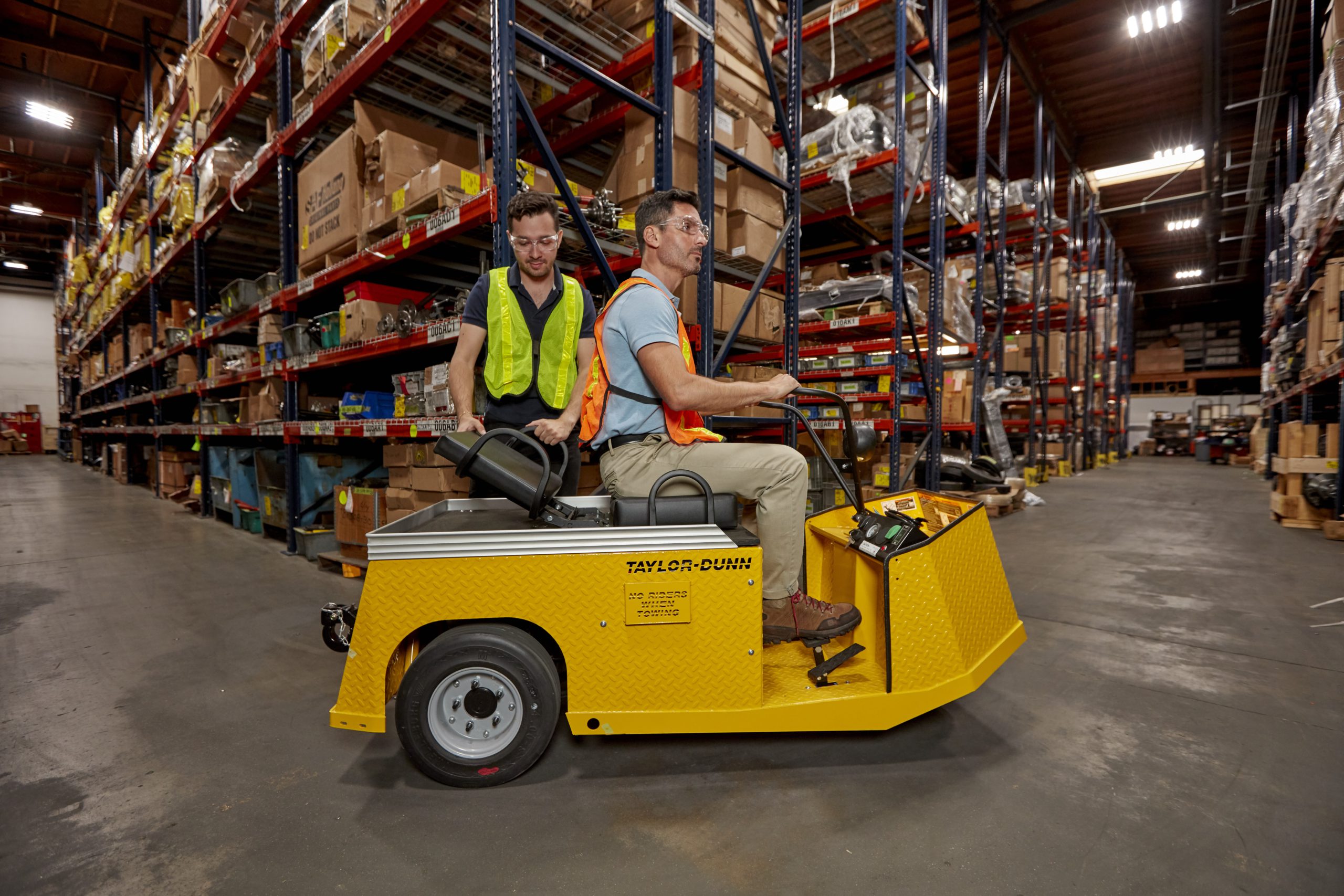 Two workers with a yellow utility vehicle in a warehouse