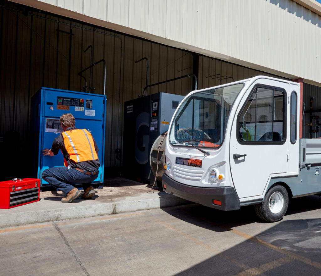 Man with a toolbox next to a white utility vehicle