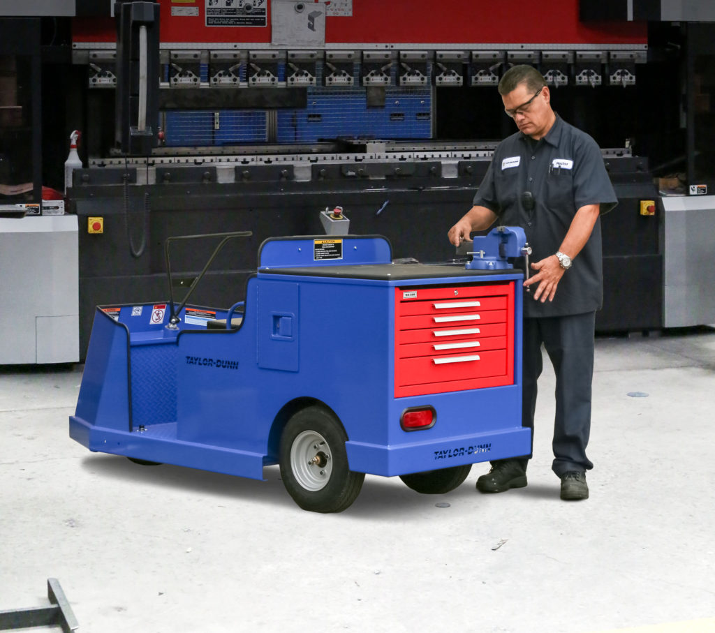 Man operating a vice grip connected to a blue utility vehicle