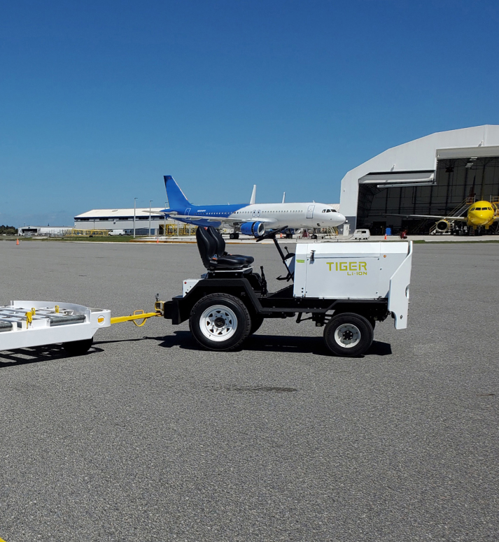 White "Tiger" utility vehicle pulling a trailer outside an airport
