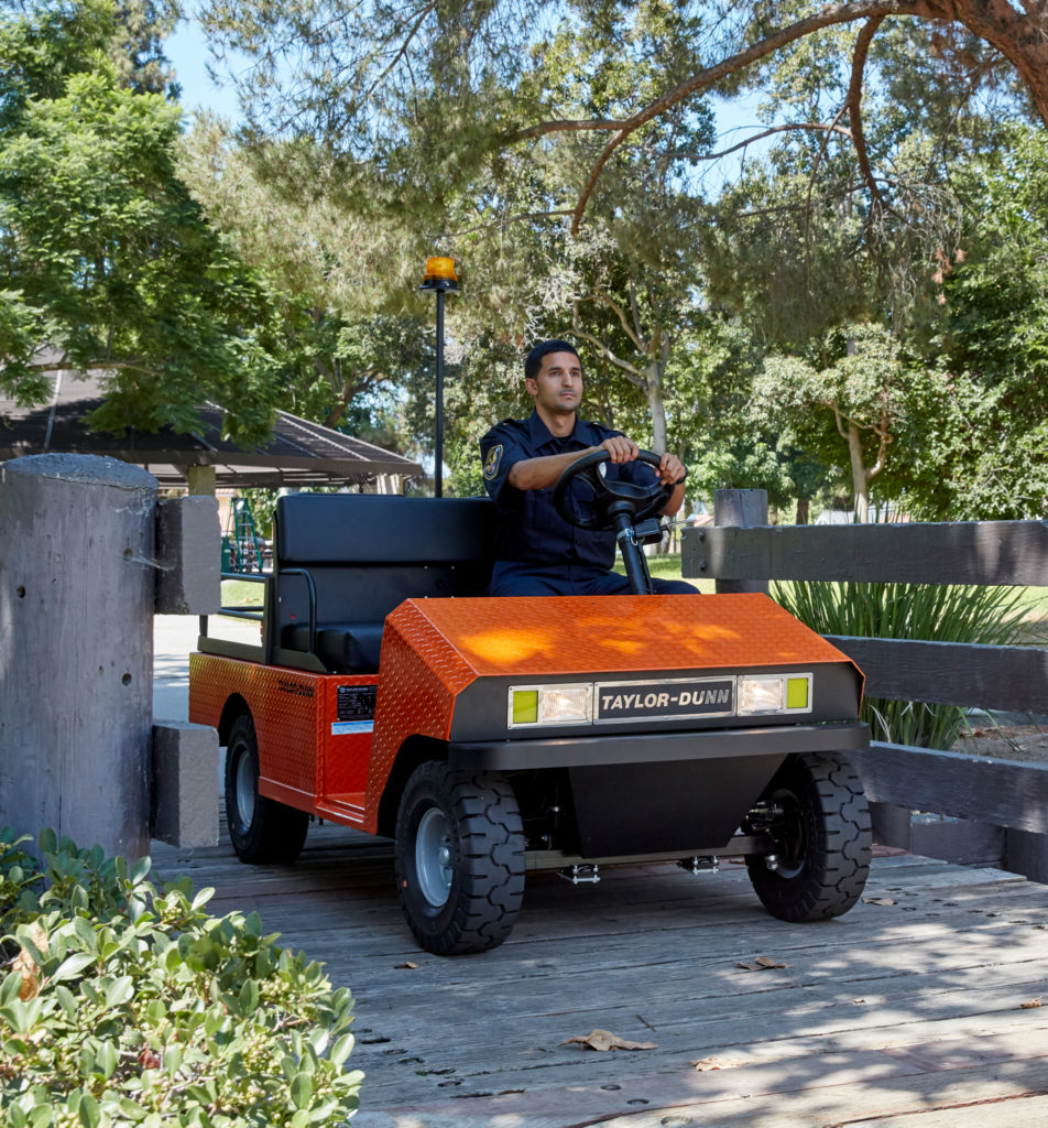 Man driving orange utility vehicle through the park