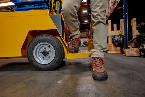 Close up of step hight detail with workers legs and boots stepping off of a utility vehicle