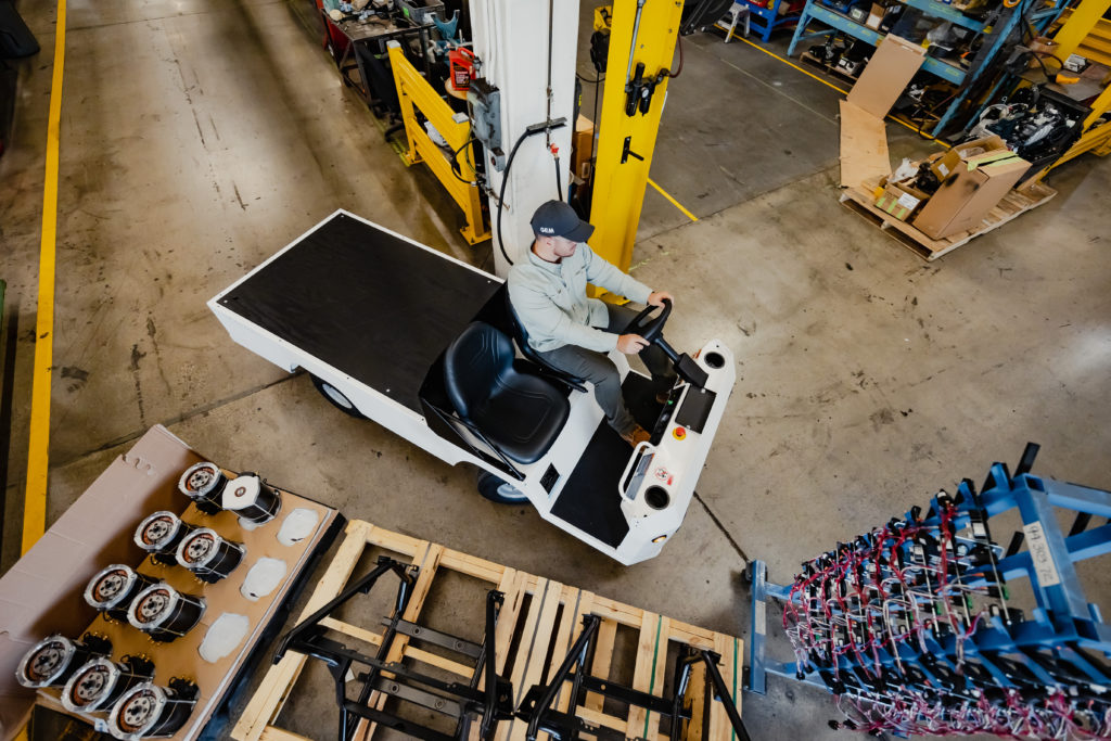 Man riding commercial utility vehicle through warehouse