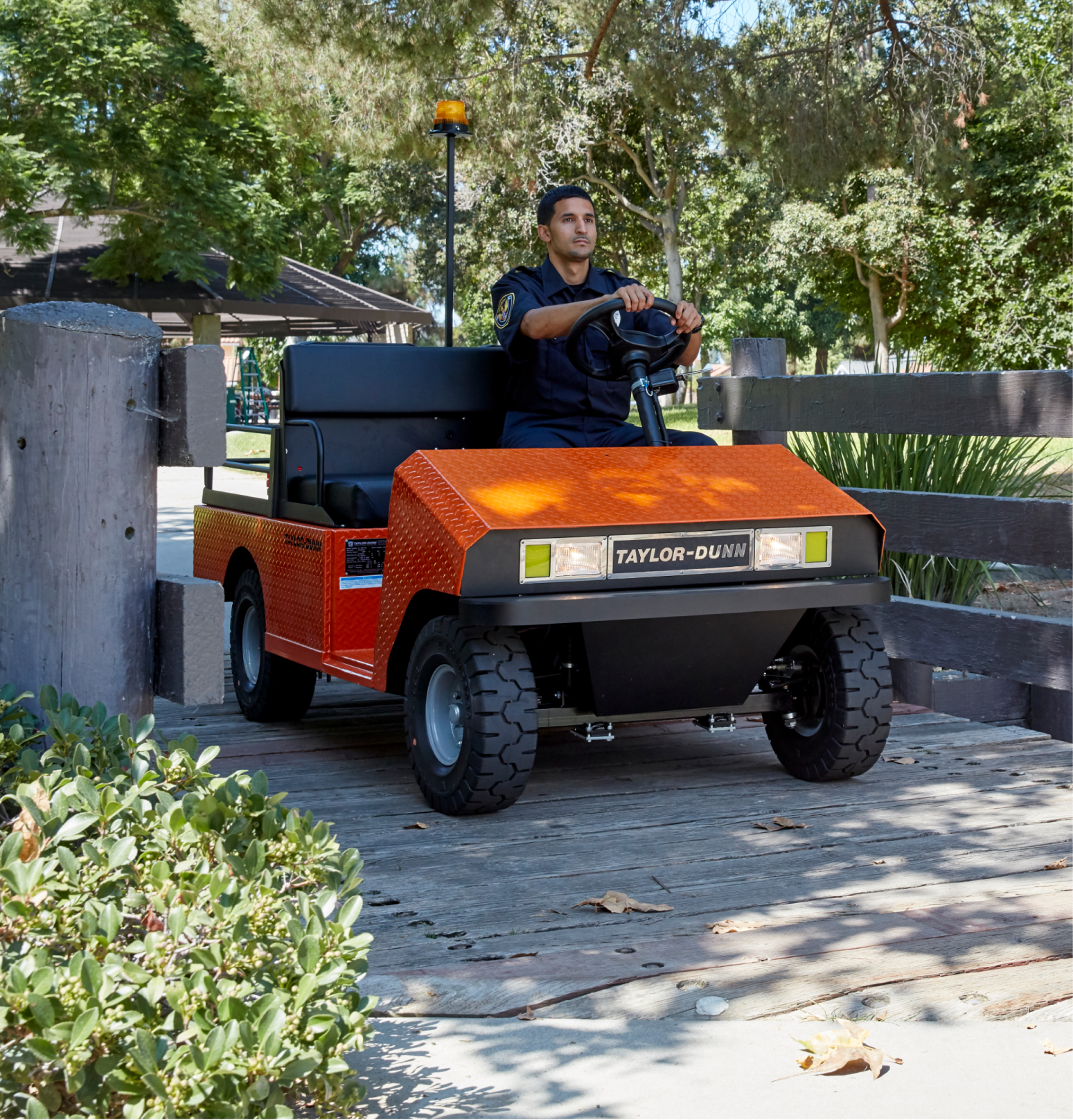 Man driving Orange safety utility vehicle through a park