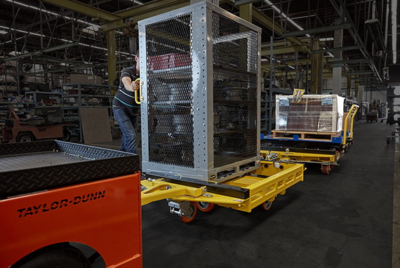 man loading cage onto a trailer in a warehouse
